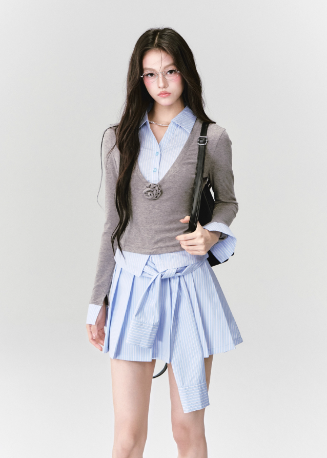 A quiet evolution of the preppy muse — the Blue Prelude Layered Shirt blends striped academia with Fragileheart’s signature delicate poise. The faux two-piece design layers a mist-grey knit over a powder-blue shirt, finished with a minimalist floral accent at the chest. A study in balance, it redefines the modern school-girl aesthetic with luxury subtlety.