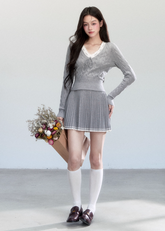Fragileheart knit skirt set, lace V-neck sweater, pleated mini skirt outfit, luxury Korean fashion, quiet luxury womenswear, pastel noir aesthetic, elegant pre-autumn outfit, grey two-piece knit set, romantic feminine fashion, K-fashion 2025, vintage-inspired knitwear, soft Korean fashion, delicate pleated skirt look, refined knit coordination