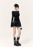 Model wearing a black pleated leather-look mini skort with a white cropped top