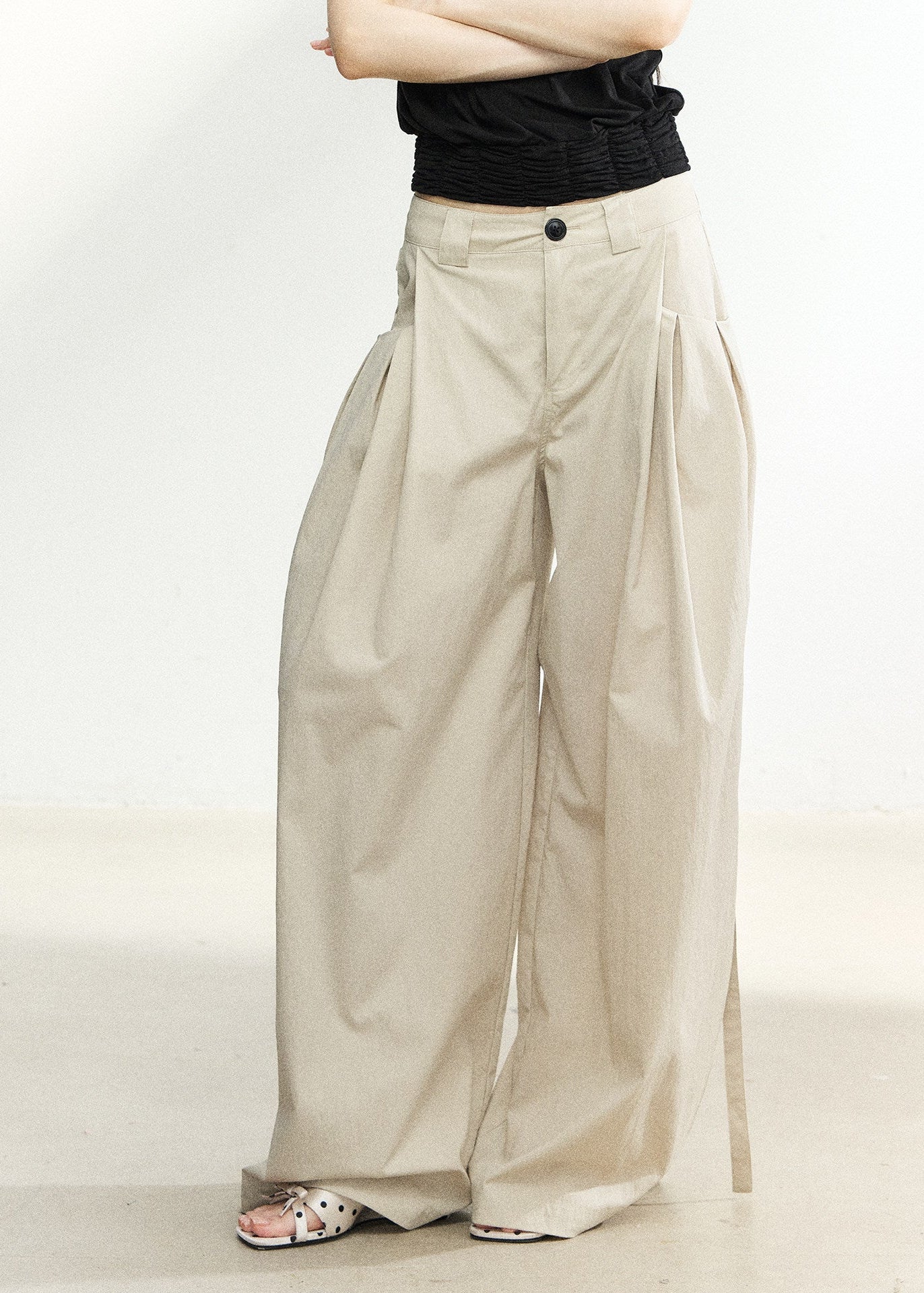 Beige high-waisted wide-leg trousers with side pleats