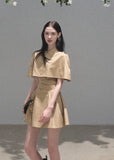 Cropped collared cape layered over a waist-defining sleeveless dress