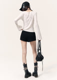 White long-sleeve top with an angel wing back print styled with a black mini skirt and cap