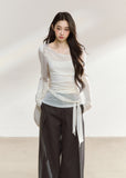 White asymmetric layered long-sleeve top with sheer panels and draped waist ties
