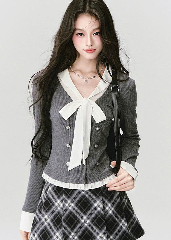 A soft rebellion in knit form — this double-breasted faux two-piece top blends vintage academia with K-fashion sensuality. The ivory bow and pleated trim contrast against charcoal grey, creating a refined silhouette that flatters with quiet confidence. Perfect for 2025 fall looks that balance grace and edge.
