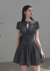 Model wearing a dark plaid short-sleeve tea dress with a fitted waist