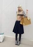Navy pleated skirt with an asymmetric hem styled with knee-high socks and brown loafers
