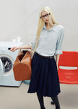 Navy pleated skirt with an asymmetric hem styled with knee-high socks and brown loafers