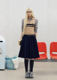 Navy pleated skirt with an asymmetric hem styled with knee-high socks and brown loafers