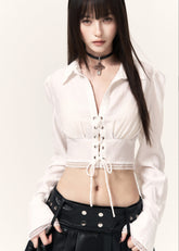White cropped shirt with a lace-up waist, pointed collar, and lace-trimmed hem