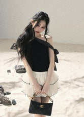 Black one-shoulder knit top with polka dot ribbon bow detail