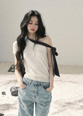 White one-shoulder knit top with black polka dot ribbon detail