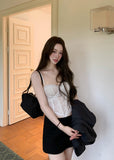 Model wearing an ivory embroidered corset camisole under a dark blazer