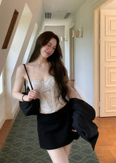 Black low-rise A-line mini skirt styled with an ivory lace camisole
