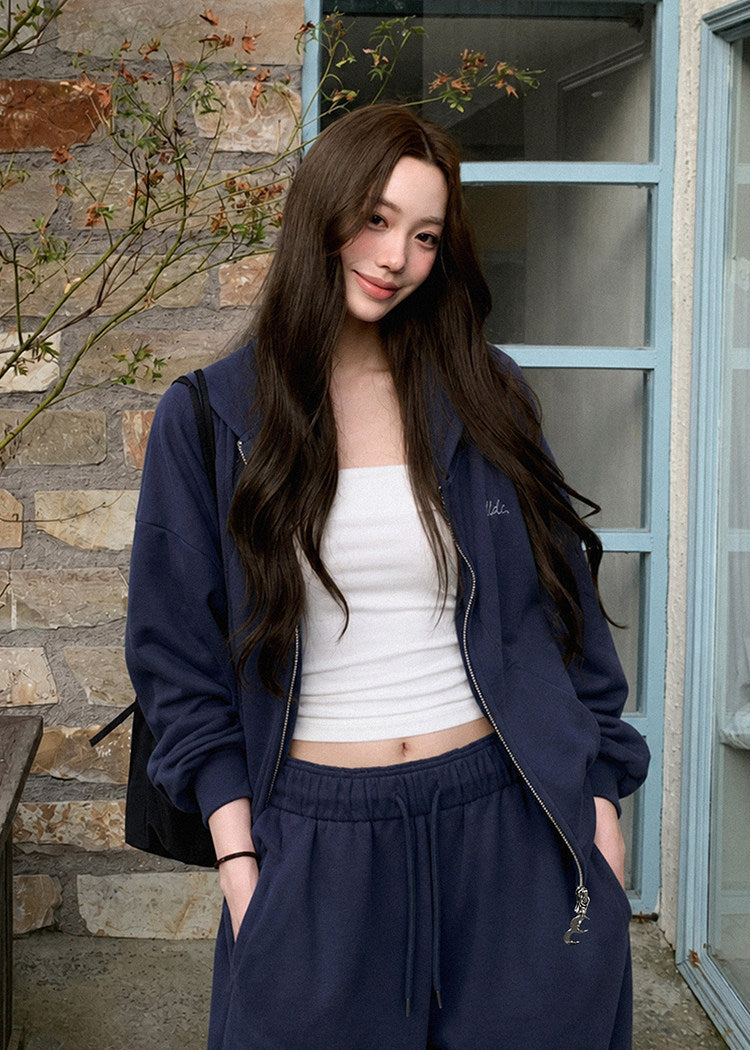 Model wearing a navy embroidered zip-up hoodie and drawstring sweatpants set