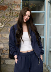 Model wearing a navy embroidered zip-up hoodie and drawstring sweatpants set