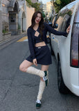 Model wearing a black ballet cardigan, camisole, and mini skirt three-piece set