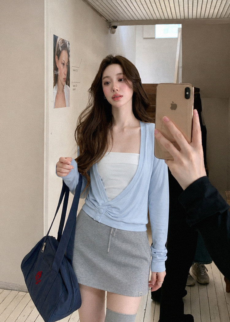 Model wearing a sky-blue asymmetric cross-twist knit top