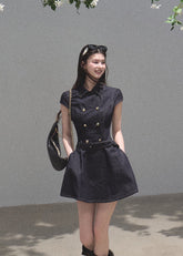 Model wearing a dark denim double-breasted mini dress with a matching belt