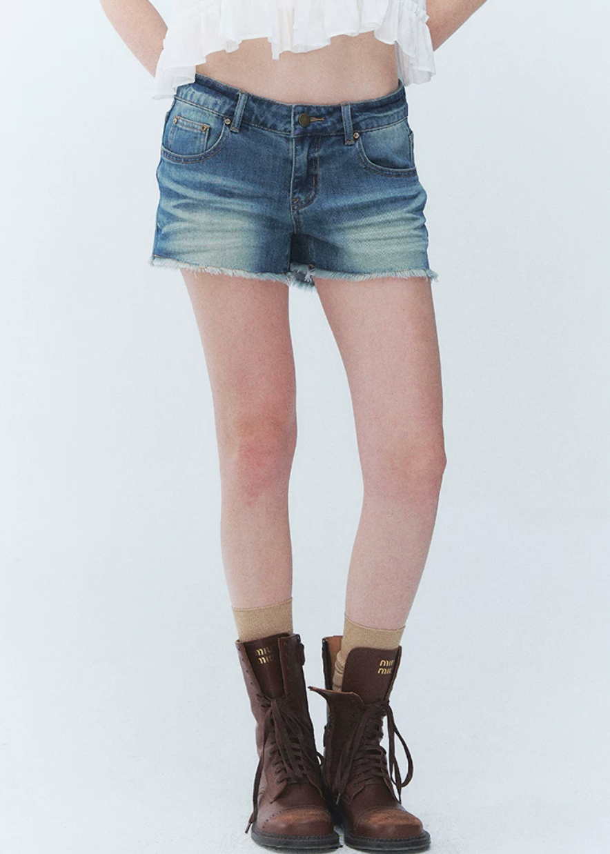 low rise denim shorts, vintage denim shorts, fringe denim shorts, distressed denim shorts, cat whisker shorts, American vintage shorts, women’s hot shorts, casual denim shorts, summer denim shorts, frayed hem shorts, Korean feminine styling, resort denim shorts, cotton blend denim shorts, washed denim shorts, vacation shorts outfit