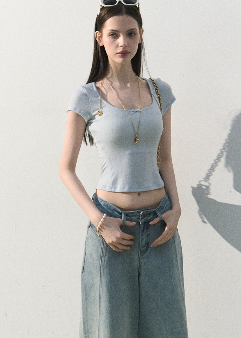 Model wearing a lace-trim cropped tee with relaxed jeans