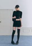 Model wearing a black half-turtleneck knit top and A-line mini skirt set