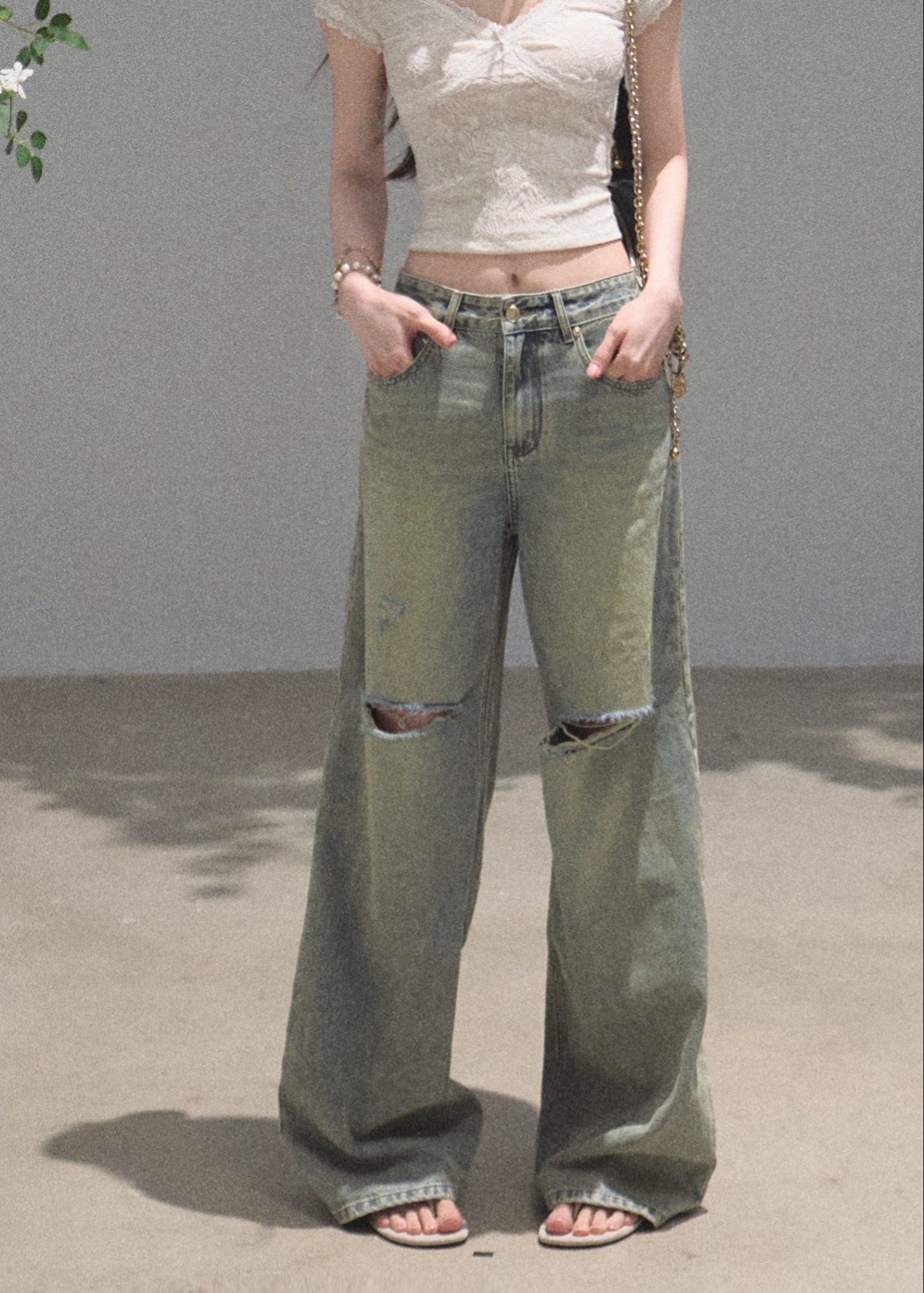Faded green wide-leg jeans with distressed knee openings