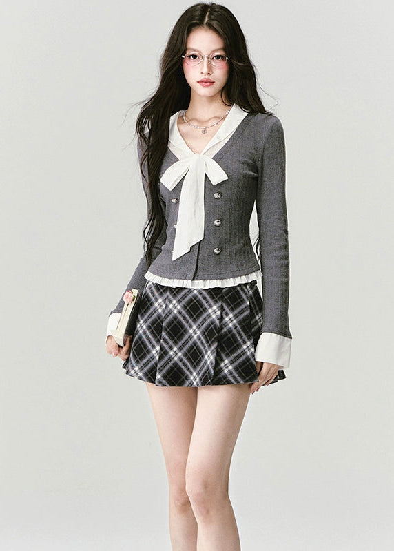A soft rebellion in knit form — this double-breasted faux two-piece top blends vintage academia with K-fashion sensuality. The ivory bow and pleated trim contrast against charcoal grey, creating a refined silhouette that flatters with quiet confidence. Perfect for 2025 fall looks that balance grace and edge.