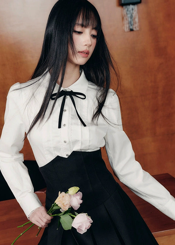 The Cherry Blossom Sonata Set captures the duality of innocence and control — a signature Fragileheart silhouette. The crisp ivory blouse, adorned with a black ribbon tie, flows into a high-waisted pleated skirt that sculpts the waist with subtle strength. Inspired by moonlit refinement and poetic order, it’s a quiet statement of authority wrapped in grace.