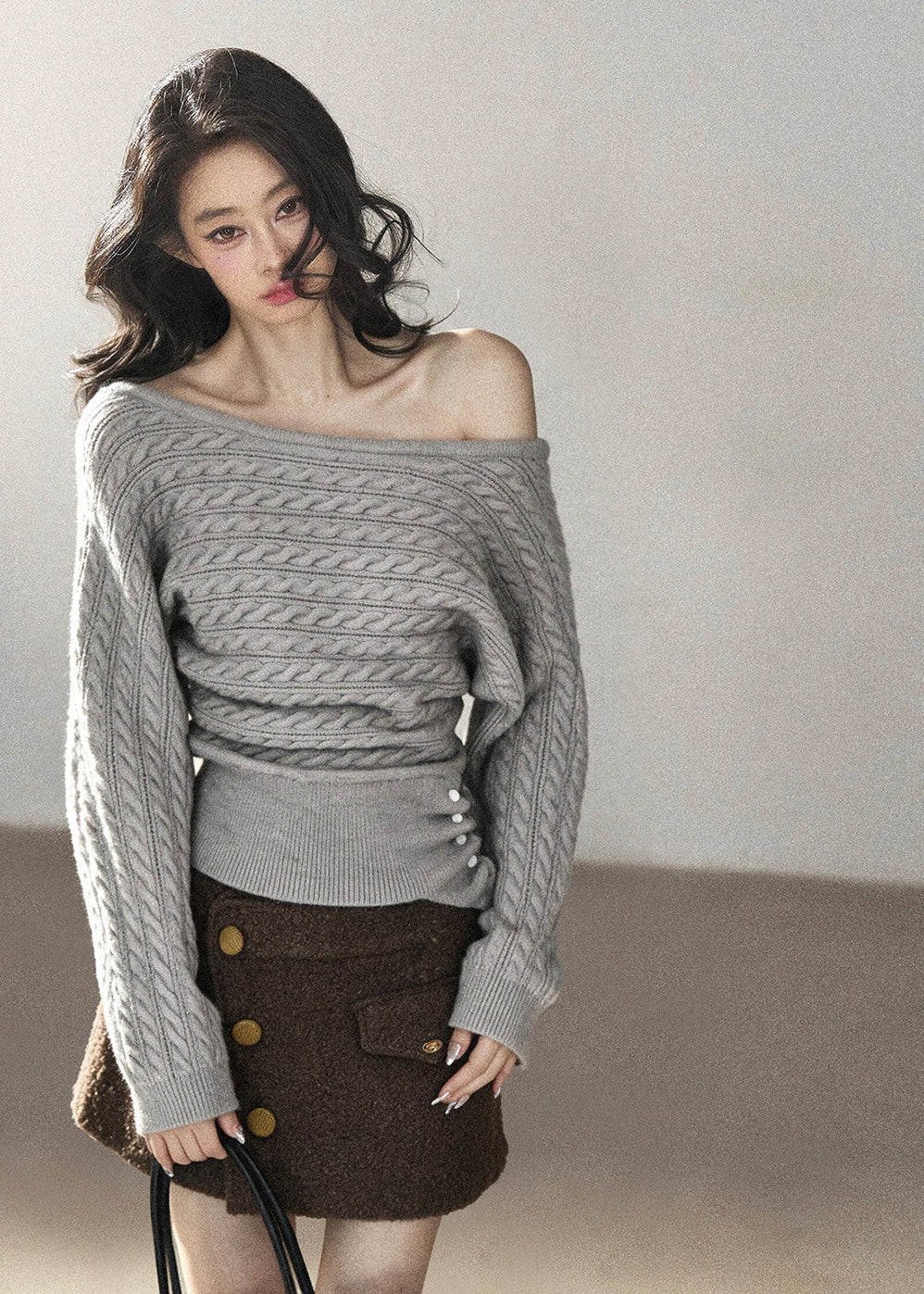 Grey one-shoulder cable knit sweater styled with a brown mini skirt