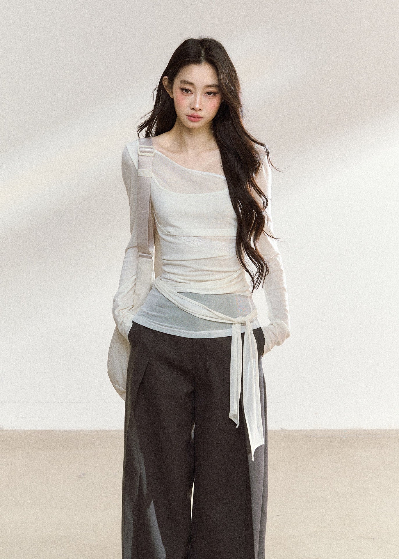 White asymmetric layered long-sleeve top with sheer panels and draped waist ties