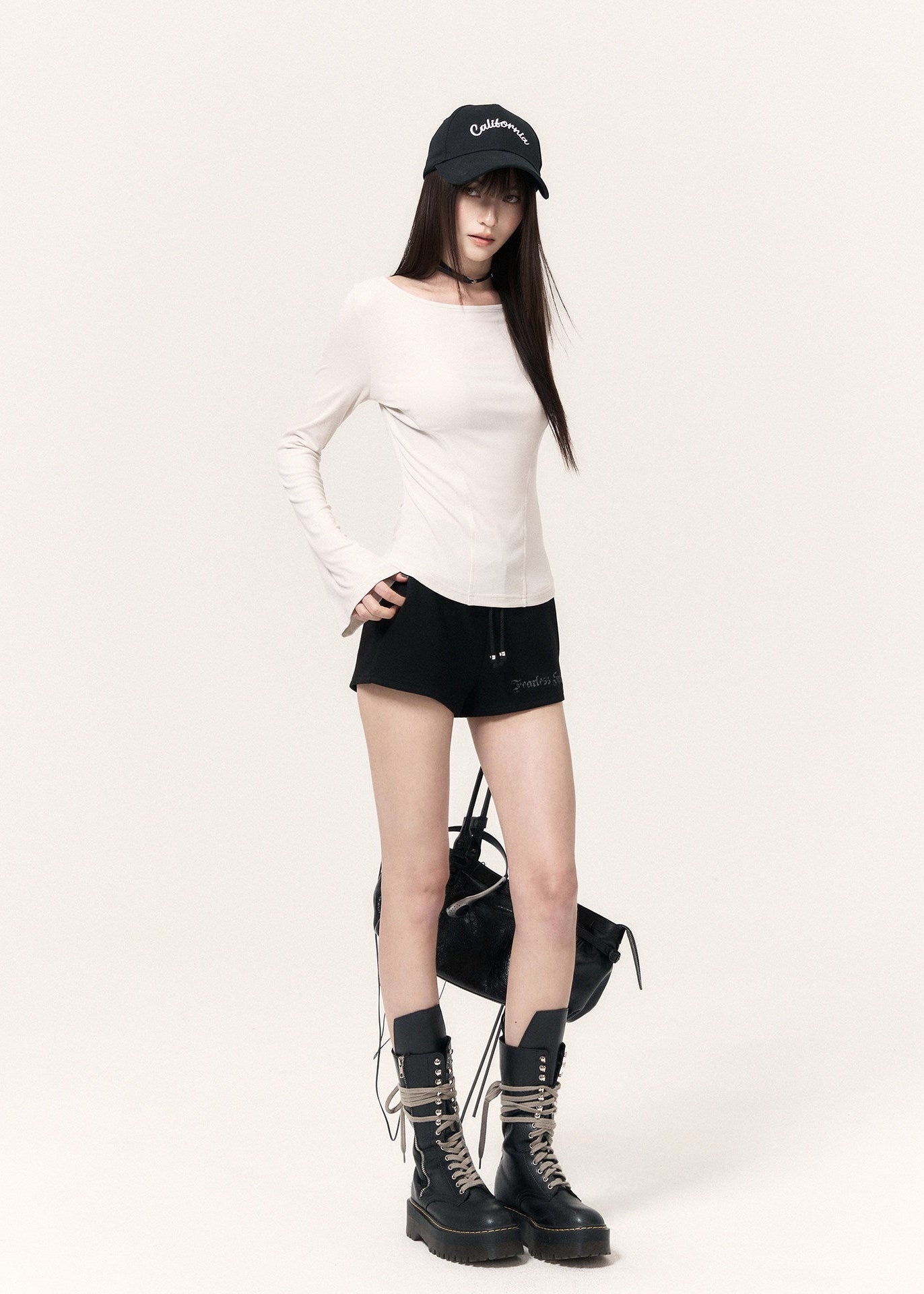 White long-sleeve top with an angel wing back print styled with a black mini skirt and cap