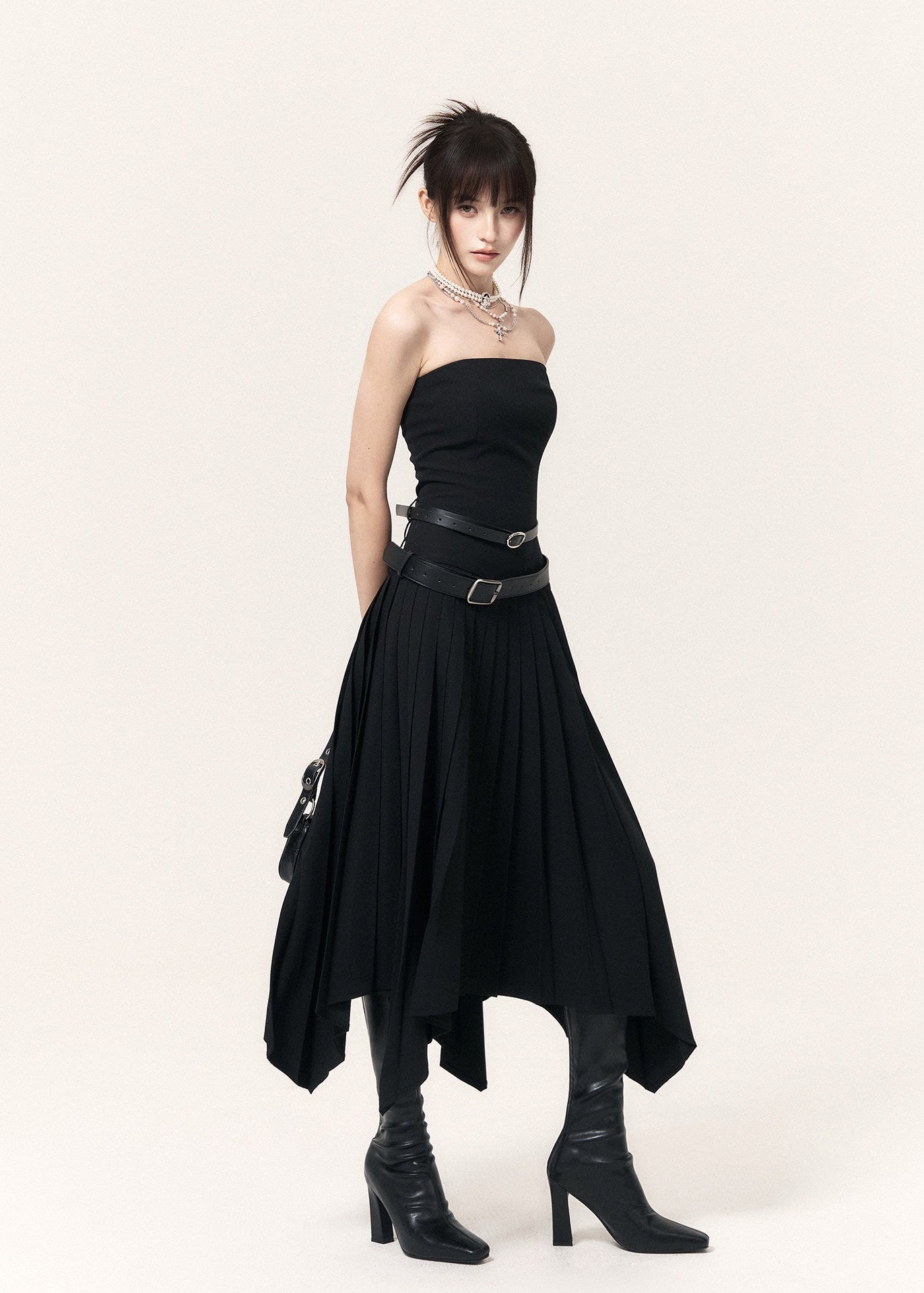 Model wearing a black irregular-hem dress with a fitted bodice and ankle boots