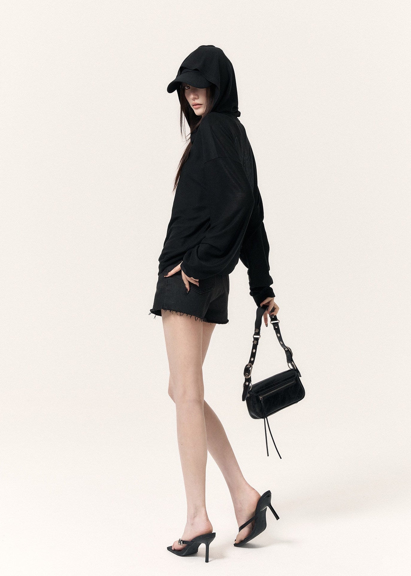 Model wearing a lightweight black hooded cardigan with distressed shorts and boots