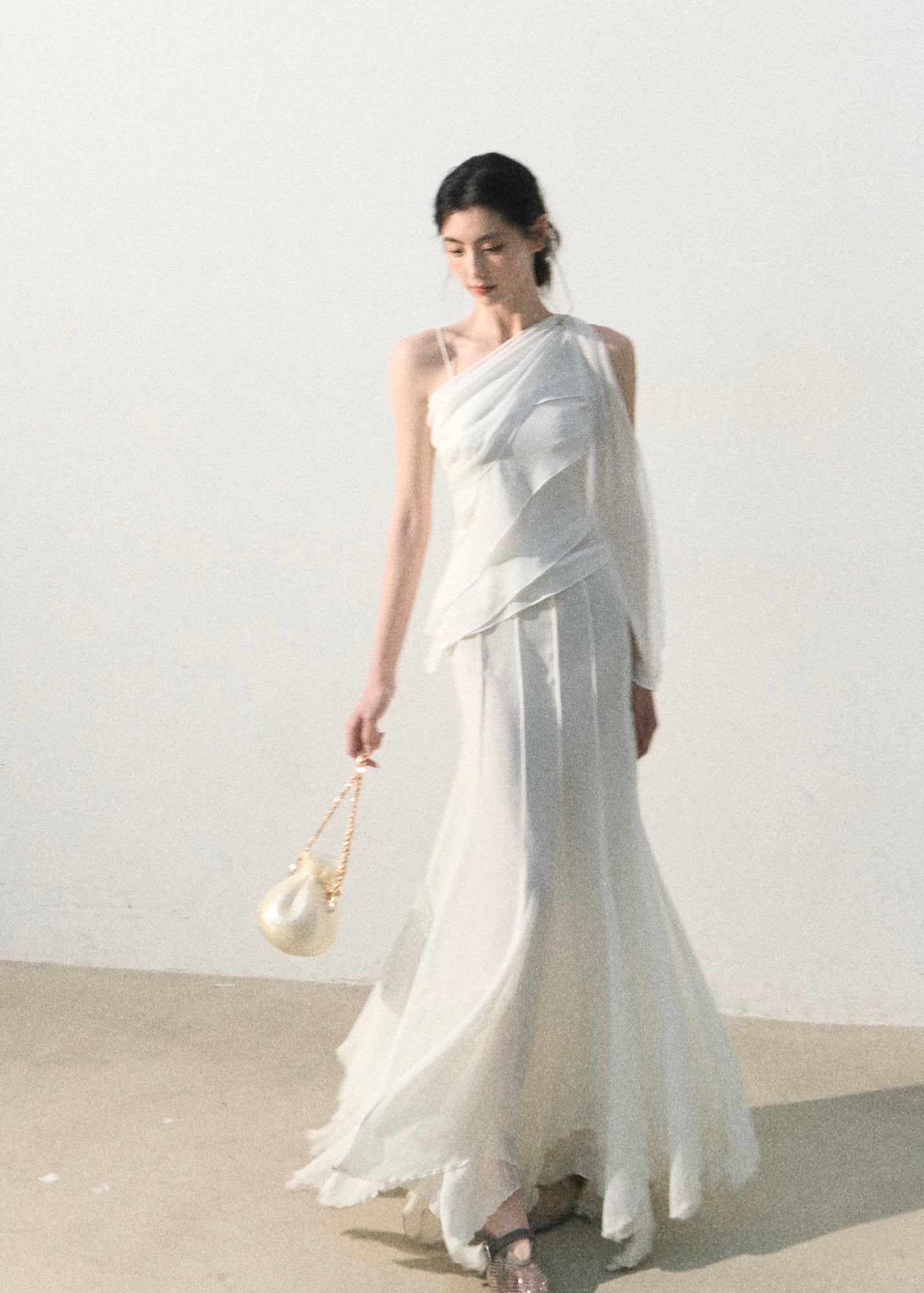 One-shoulder white top with soft layered drape detail