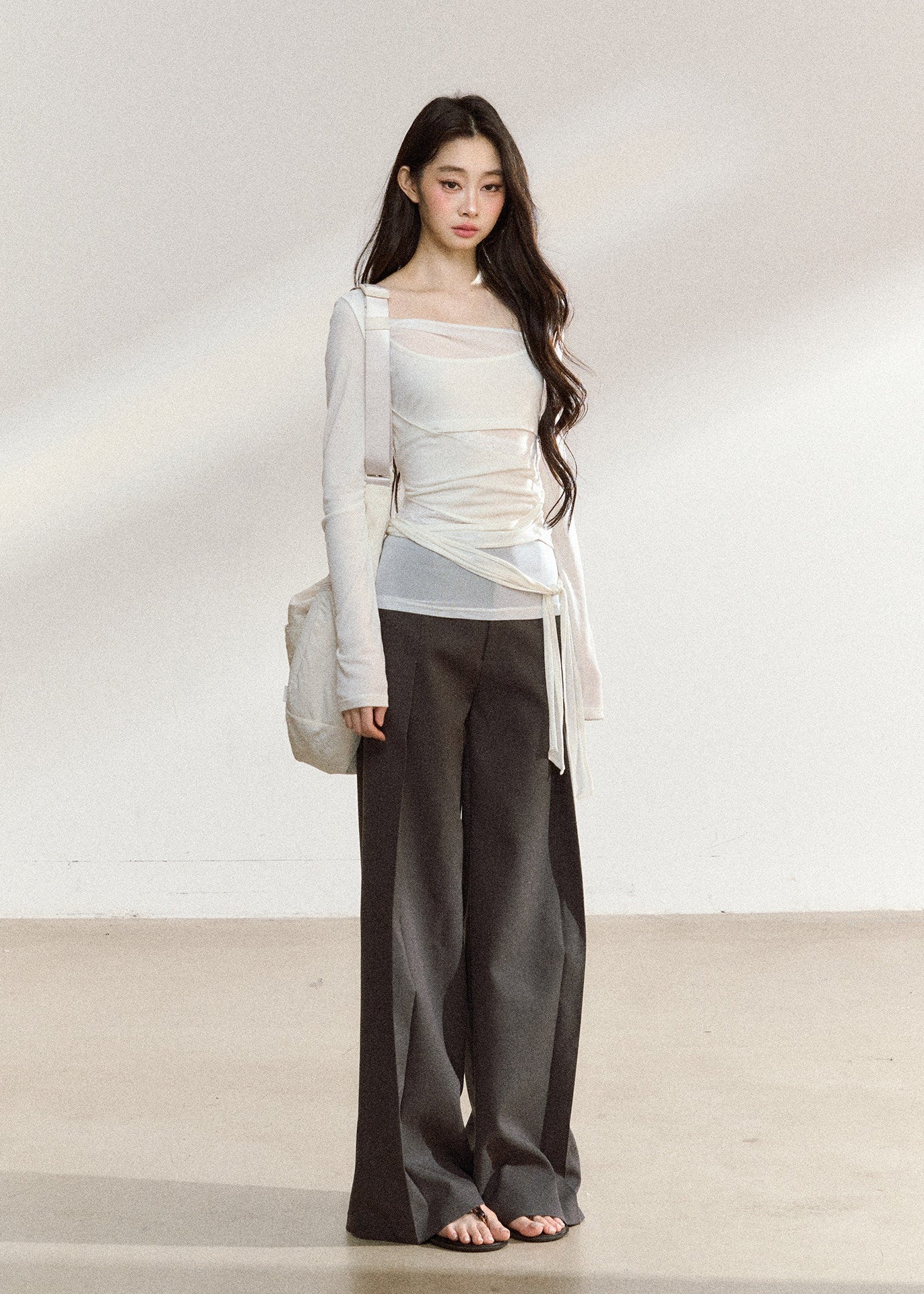 White asymmetric layered long-sleeve top with sheer panels and draped waist ties