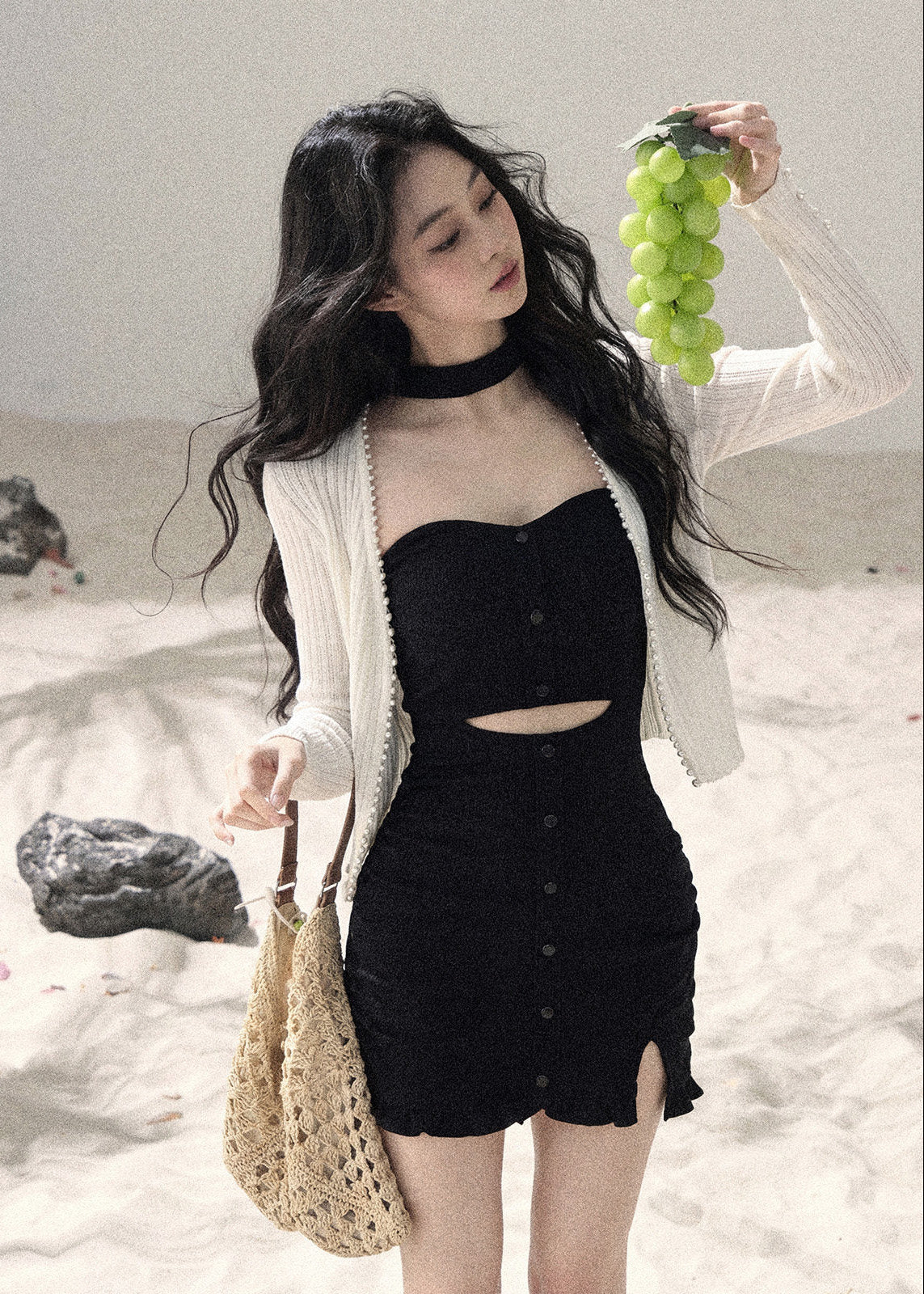 Woman wearing black halter cutout knit mini dress layered with white cardigan