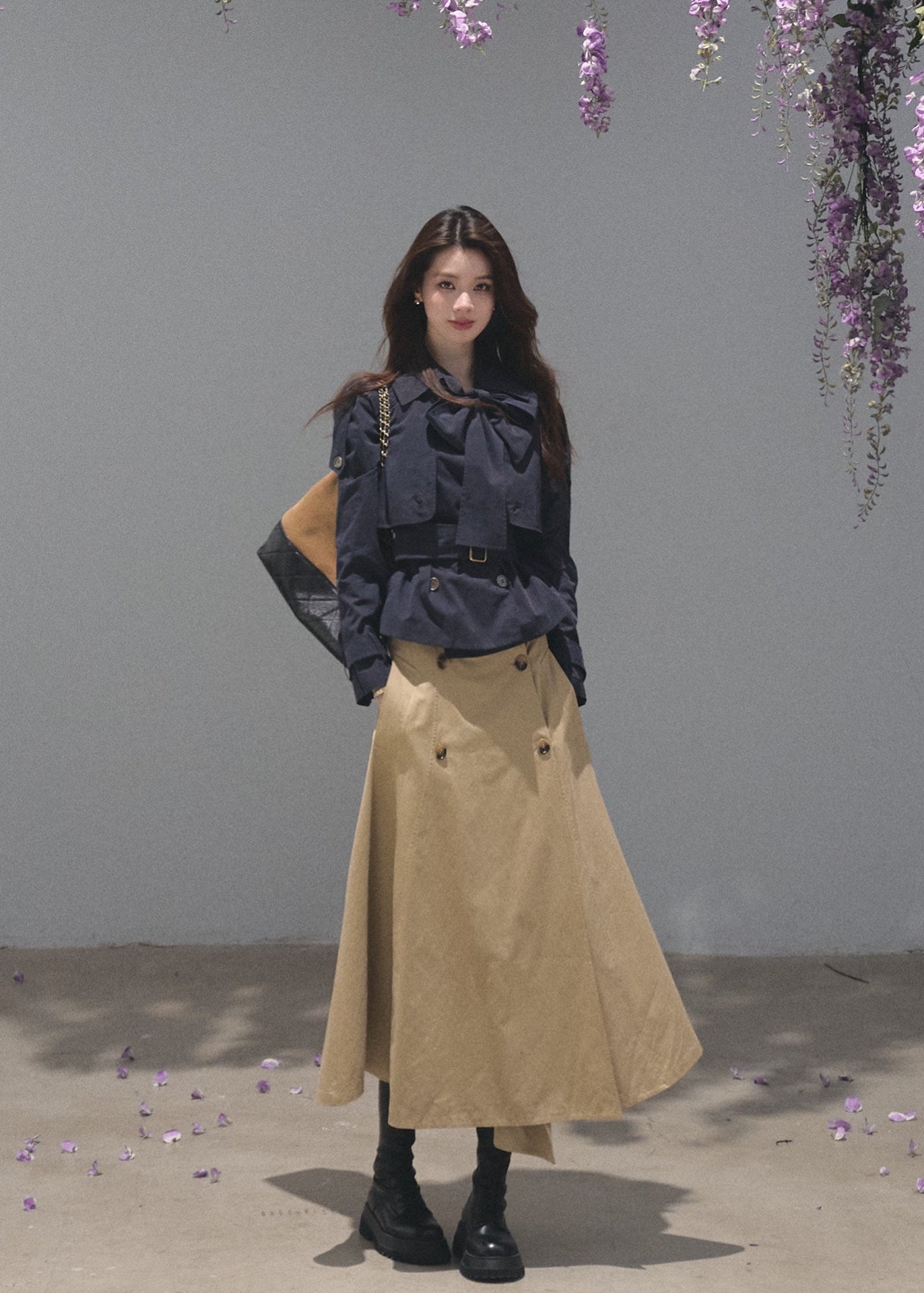 Black bow-neck jacket paired with a khaki belted midi skirt
