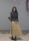 Black bow-neck jacket paired with a khaki belted midi skirt