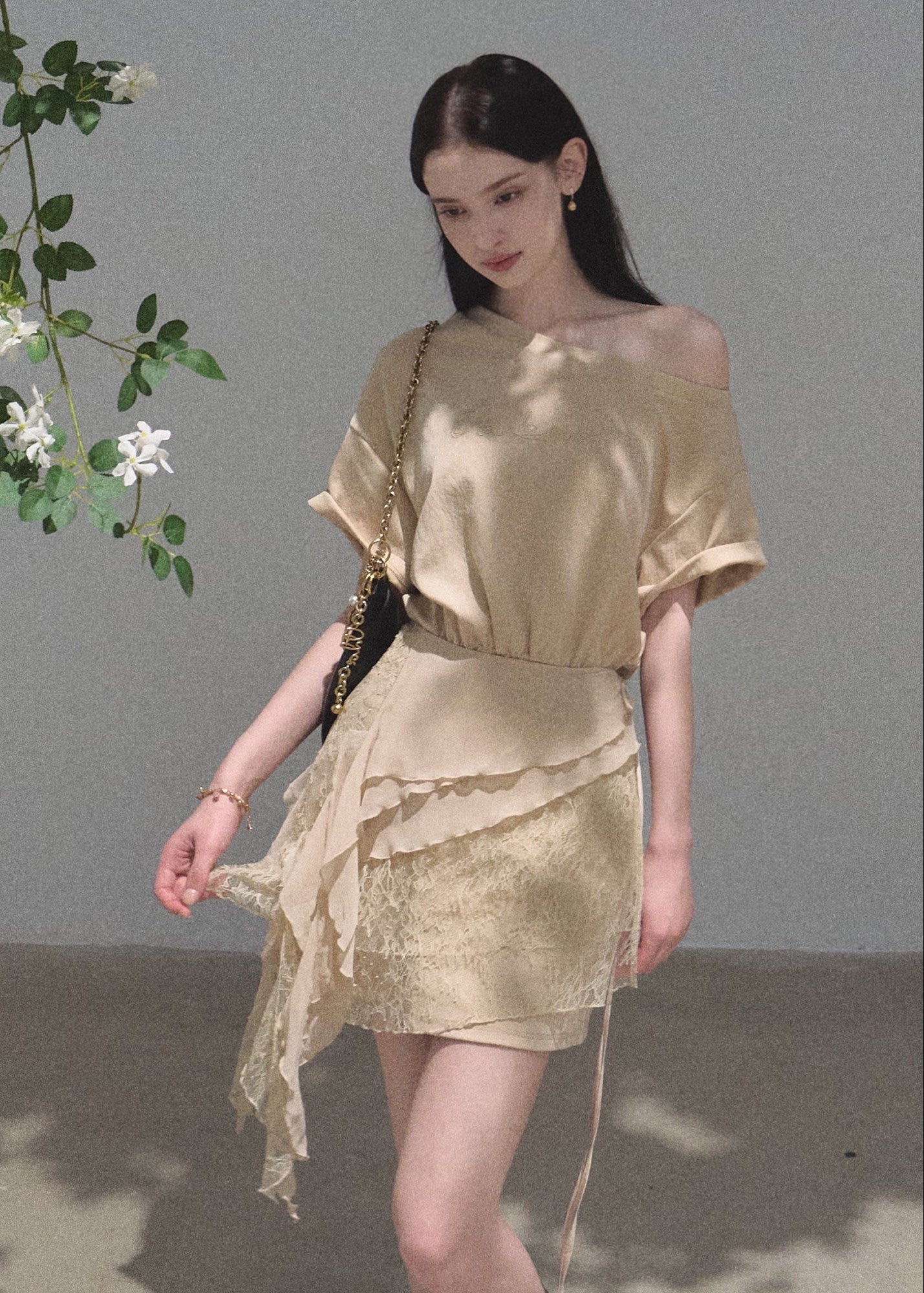 Model wearing a beige asymmetric mini dress with a lace apron overlay