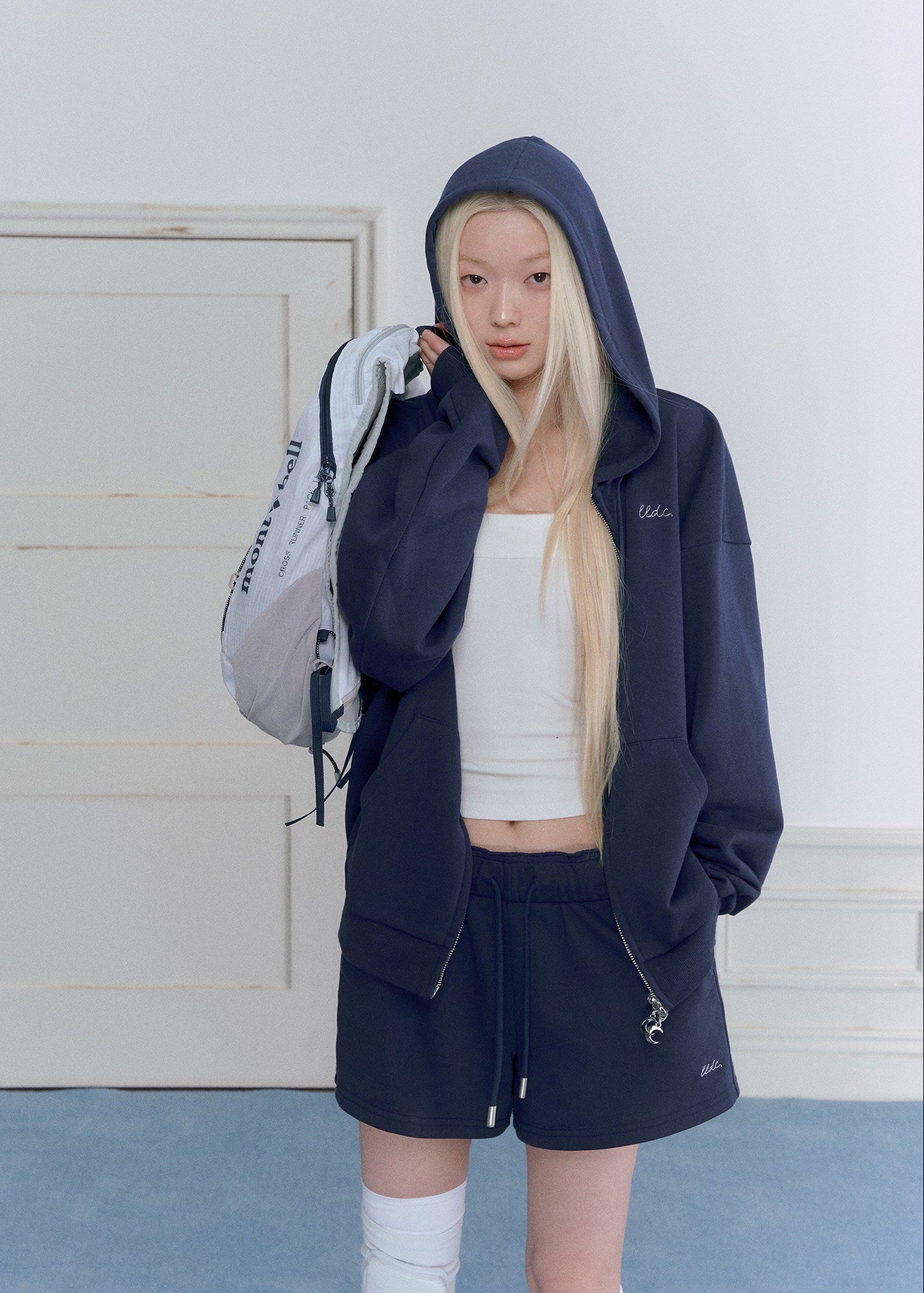 Model wearing a navy embroidered zip-up hoodie and drawstring sweatpants set