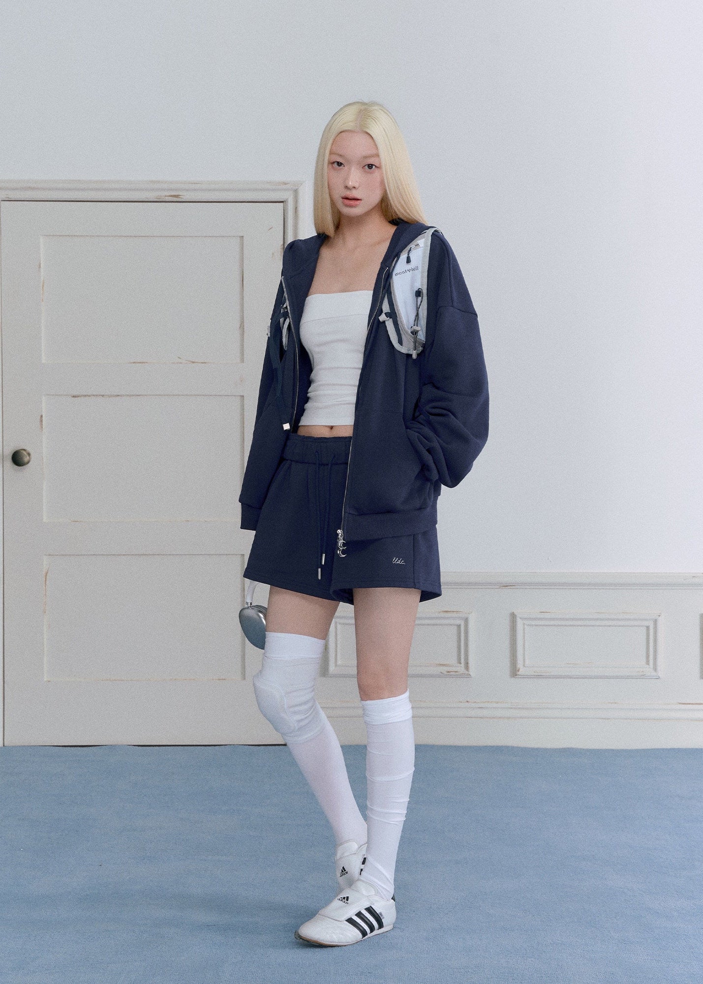 Model wearing a navy embroidered zip-up hoodie and drawstring sweatpants set
