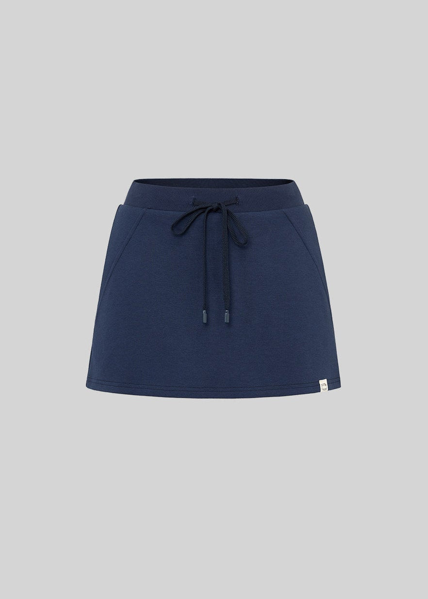 Model wearing a navy and white faux-layered top with a drawstring mini skirt
