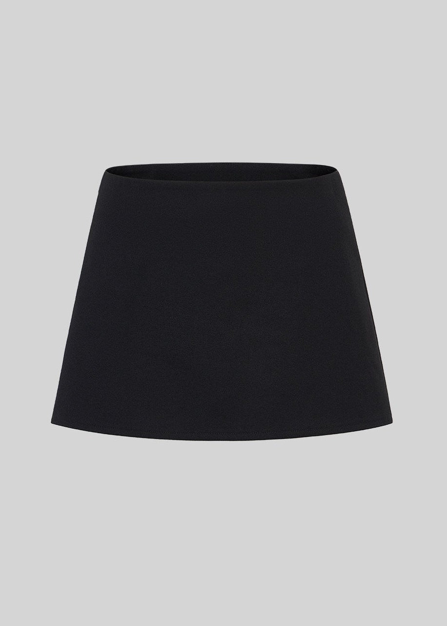 Model wearing a black A-line mini skirt with sheer knee-high socks and black shoes
