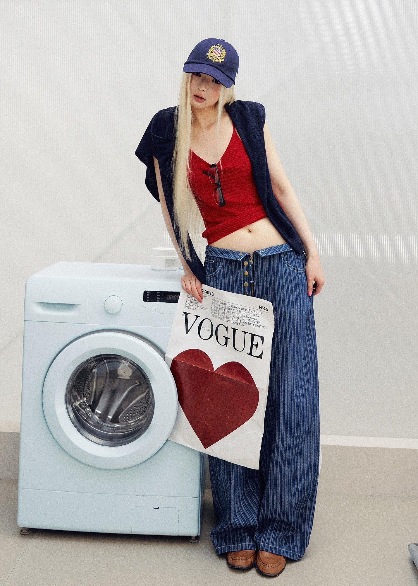 1. Model wearing a fitted red knit camisole with a low neckline and a navy cap