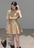 Model wearing a khaki cape-overlay mini dress with a matching belt