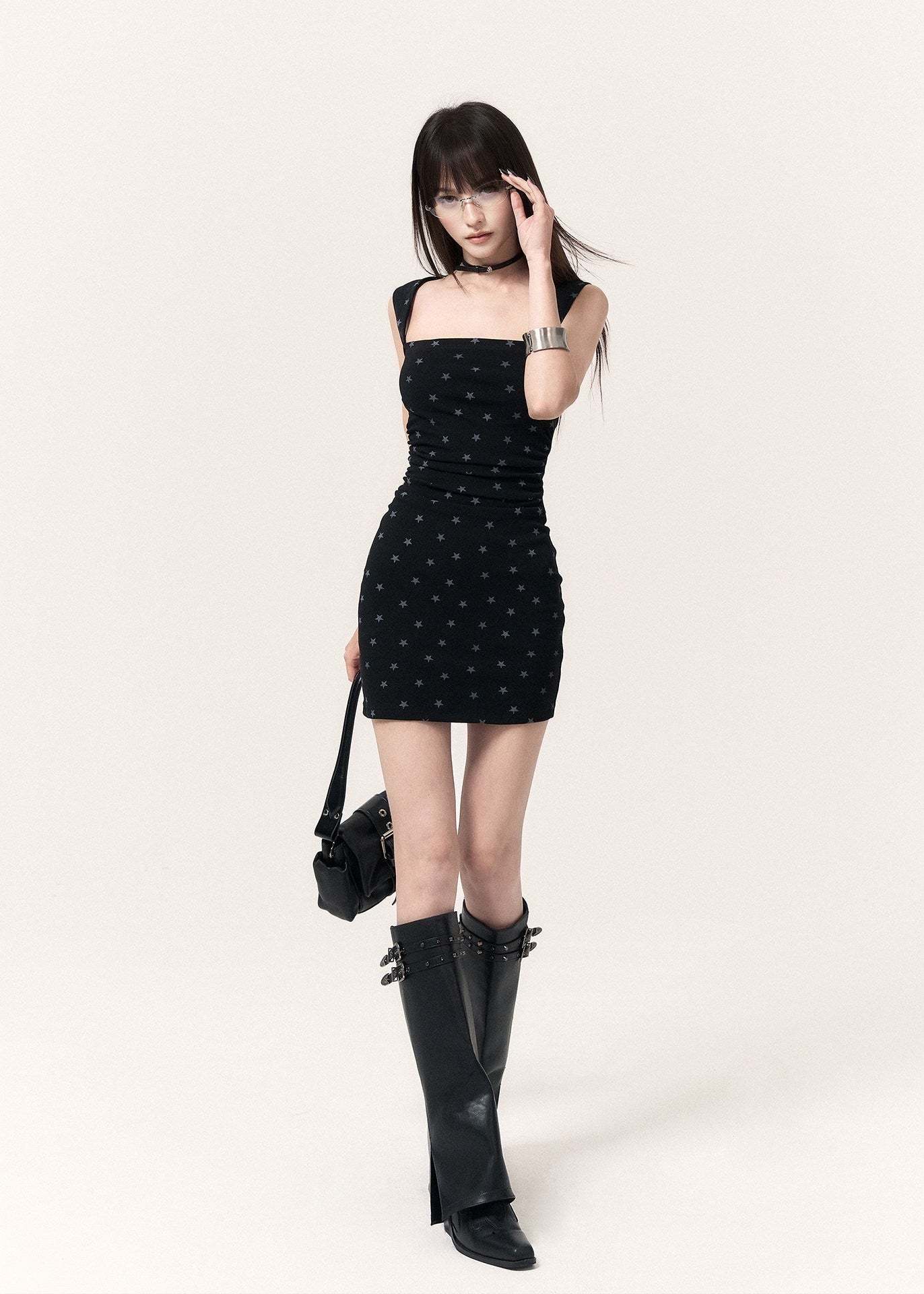 Model wearing a black star print mini dress with knee-high boots