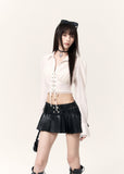 Model wearing a black pleated leather-look mini skort with a white cropped top