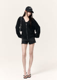 Model wearing a lightweight black hooded cardigan with distressed shorts and boots