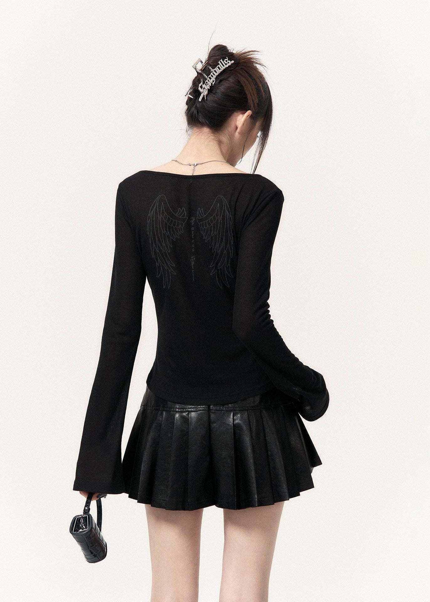 Black fitted long-sleeve top with flared cuffs styled with a pleated mini skirt