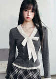 A soft rebellion in knit form — this double-breasted faux two-piece top blends vintage academia with K-fashion sensuality. The ivory bow and pleated trim contrast against charcoal grey, creating a refined silhouette that flatters with quiet confidence. Perfect for 2025 fall looks that balance grace and edge.